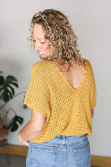 Back view of crochet top in golden yellow. It has a delicate lace pattern and a scallop trim on the v-neck back opening. thumbnail