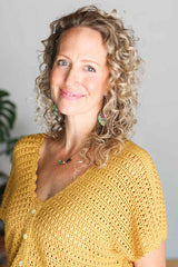 Cropped front view of crochet top, made in a golden yellow yarn. It has a narrow front button band and a v-neck opening with a scallop trim.  thumbnail