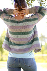 Back view of striped crochet cardigan worn over tank top and jeans. The cardigan is made in pale purple, dark sage green, pale grey, and oatmeal.  thumbnail