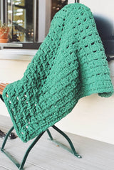 Plush green crochet throw draped over patio chair on front porch.  thumbnail