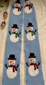 Close up of tunisian crochet scarf with snowmen  motif. The snowman have top hats and either red or green scarves.  thumbnail