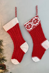 Two knit stockings hanging on a pale wall with a tiny sliver of a Christmas tree on the left side.  thumbnail