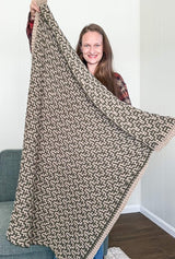 Woman holding mosaic crochet afghan up toward camera.  thumbnail