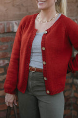 Cropped front view of knit cardigan, showing raglan increases and narrow ribbing on collar, front opening, hem, and sleeve cuffs.  thumbnail