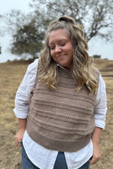 Cropped front view of woman wearing knit vest over white button up.  thumbnail