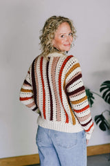 Back view of crochet cardigan, showing vertical stripes in cream, red-orange, pale peachy orange, dark red, and golden yellow. The lower hem is all in cream.  thumbnail
