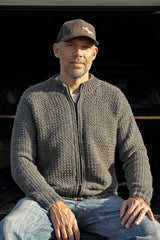 Man sitting, wearing grey crochet cardigan zipped to neck.  thumbnail