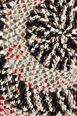 Close up of the center of a circular blanket. It's made in a super bulky weight chenille yarn in a multi color black/brown/beige/cream, and a beige worsted weight wool.  thumbnail