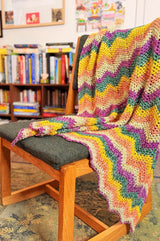 Crochet ripple throw draped over back of desk chair, in front of low bookcases.  thumbnail