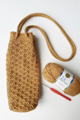 Flat lay of water bottle holder with long strap, crochet hook, and ball of yarn.  thumbnail