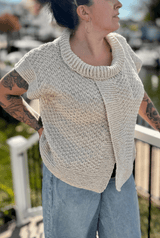 Front view of woman standing on a deck wearing a short sleeve sweater. The sweater has an overlapped open front and a short collar around a scoop neck.  thumbnail