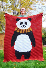 Woman holding afghan toward camera. The afghan covers her from shoulder to ground.  thumbnail