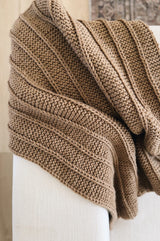 Alternate top down view of knit afghan laid over white couch.  thumbnail