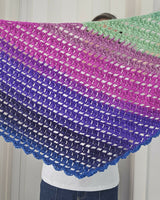 Person holding up handmade crochet triangle shawl showing bold self-striping color changes thumbnail