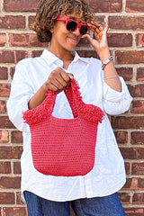 Woman in sunglasses holding crochet bag in front of a brick wall.  thumbnail