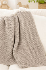 Neutral baby blanket draped on white couch thumbnail