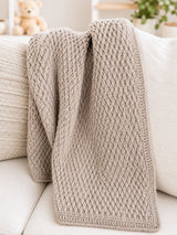 Neutral baby blanket draped on white couch thumbnail