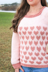 woman wearing a light pink crocheted heart motif sweater outdoors thumbnail