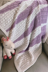 Purple and white baby blanket draped on a chair thumbnail
