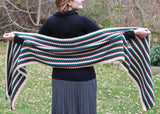 woman wearing a long teal, white, and red striped crocheted super scarf wrap outdoors thumbnail