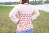 woman wearing a light pink crocheted heart motif sweater outdoors thumbnail