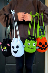 person holding four Halloween crochet treat bags in the shape of a black cat ghost frankenstein monster and jack-o-lantern thumbnail