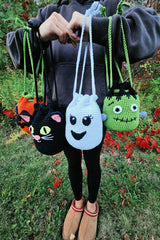 person holding four Halloween crochet treat bags in the shape of a black cat ghost frankenstein monster and jack-o-lantern thumbnail