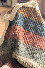 baby hiding behind striped crochet blanket with white border thumbnail