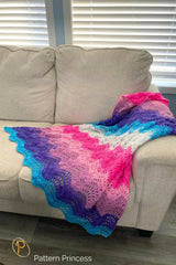 Blue, purple, pink and white baby blanket draped over couch thumbnail