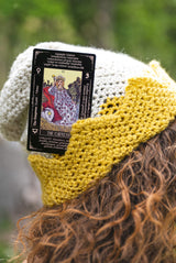 Crochet hate with gold crown border with a tarot card tucked into the rim thumbnail