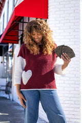 Woman wearing sweater with heart pocket holding tarot cards thumbnail