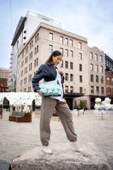 Crochet crossbody bag with tassels on a model standing on a rock thumbnail