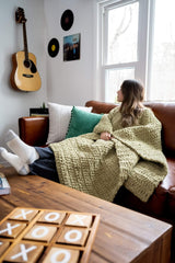 girl wearing a crochet blanket/poncho on a couch thumbnail