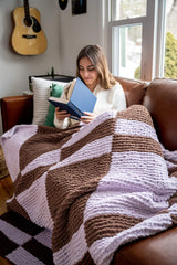 Girl reading book under knit blanket thumbnail