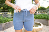 Woman tying bow on drawstring of blue knit shorts thumbnail