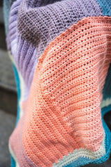 closeup of crochet blanket showing salmon, purple, and blue hues thumbnail
