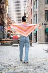 woman holding out the sides of the crochet shawl so entire shawl shape can be seen thumbnail
