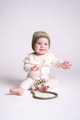 baby on the floor wearing knit hat playing with knit mittens thumbnail