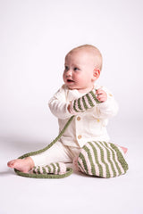 baby on the floor wearing knit hat playing with knit mittens thumbnail