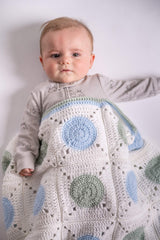 baby posing with granny square blanket wrap made with green blue and white yarns thumbnail