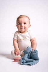 baby holding blue knit kitty lovey in front of white background thumbnail