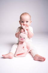 Baby holding pink crocheted bunny lovey thumbnail