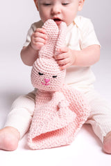Baby holding pink crocheted bunny lovey thumbnail
