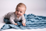 Baby laying on crochet ripple blanket in contrasting blue tones thumbnail