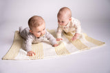 babies on knit yellow and cream striped blanket in front of a white background thumbnail