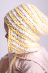 side view of white and yellow baby hat with flaps on baby thumbnail