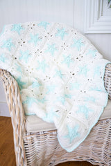 White granny square blanket with blue glow in the dark stars and border on a chair thumbnail