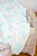 White granny square blanket with blue glow in the dark stars and border on a chair thumbnail
