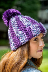 Woman wearing purple and multicolor striped hat with pom thumbnail