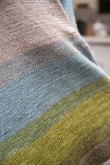 close up of knit blanket showing greens blues and greys thumbnail